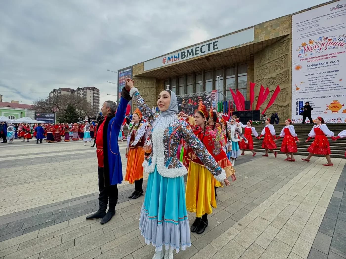 Танцовщица в народном костюме на фоне баннера республиканского праздника «Масленица» в Дагестане