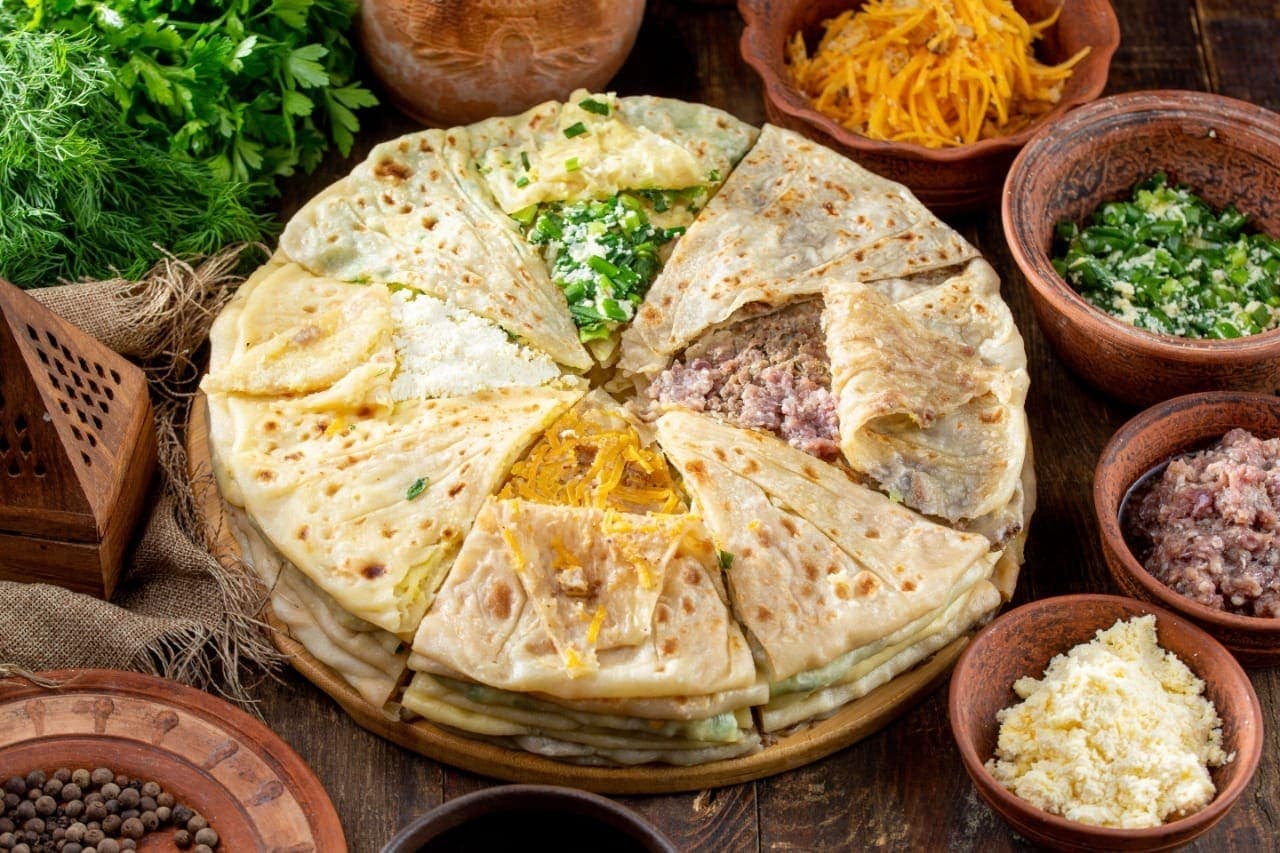 Круглое чуду, разрезанное на дольки с разными начинками — мясо, творог, зелень, тыква