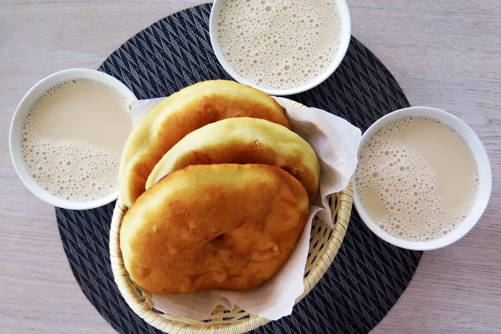 Три пиалы калмыцкого чая с молочной пенкой рядом с корзинкой жареных борцоков