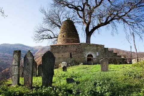 Древнее кладбище с каменными стелами у мавзолея с конусообразным куполом в горах Дагестана