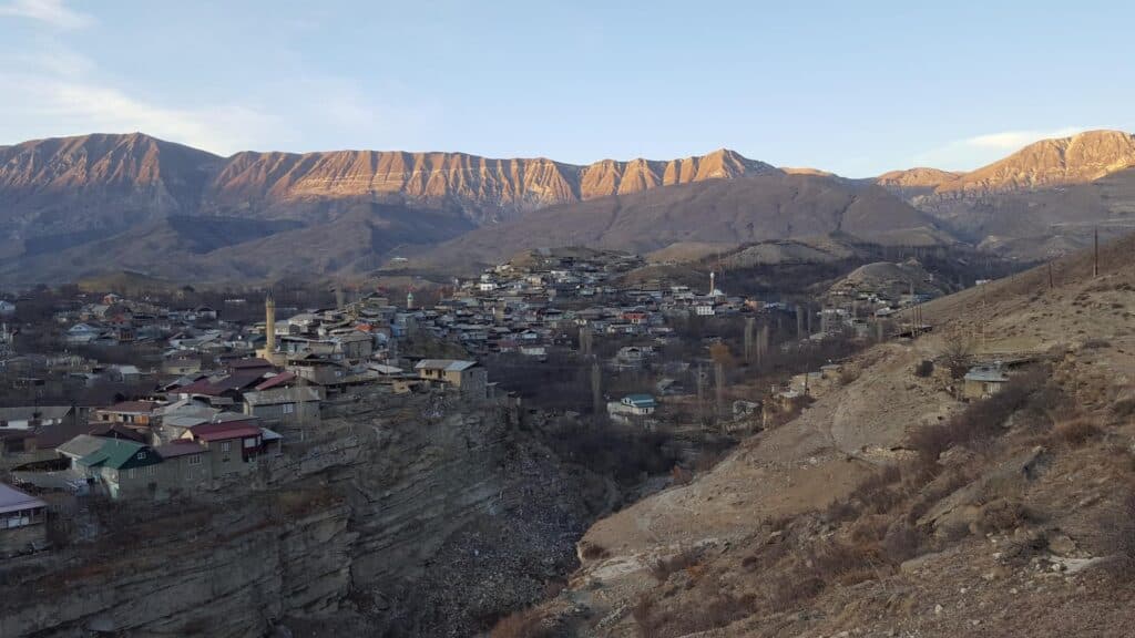 Панорама села Ботлих на закате на фоне освещённого солнцем Андийского хребта