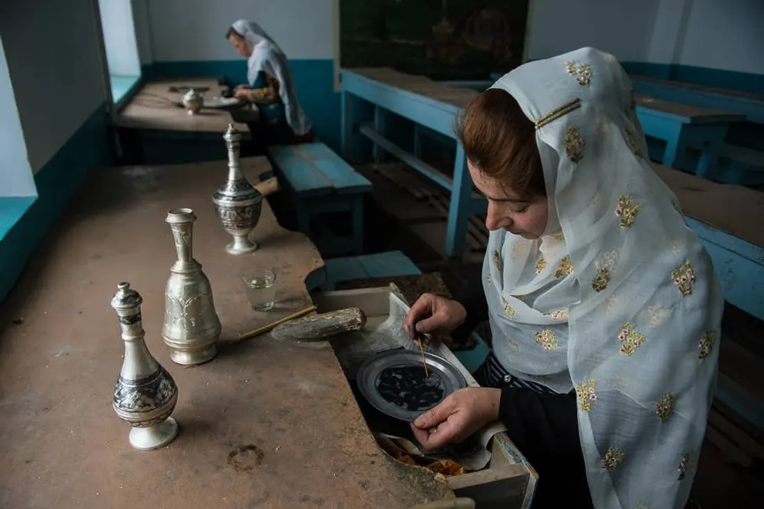 Кубачинская мастерица наносит чернь на серебряный кувшин за рабочим столом
