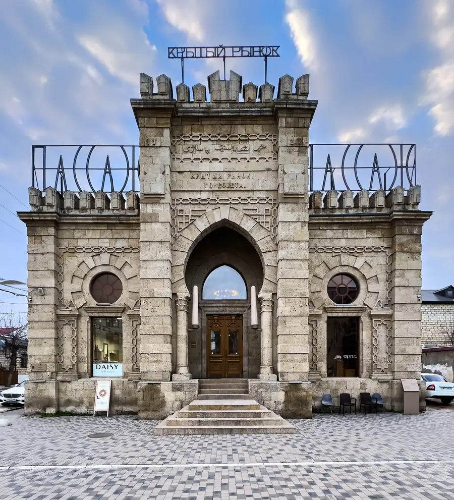 Здание Пассажа в Дербенте — крытый рынок 1916–1926 годов постройки с зубчатым верхом и кованой вывеской «Пассаж»
