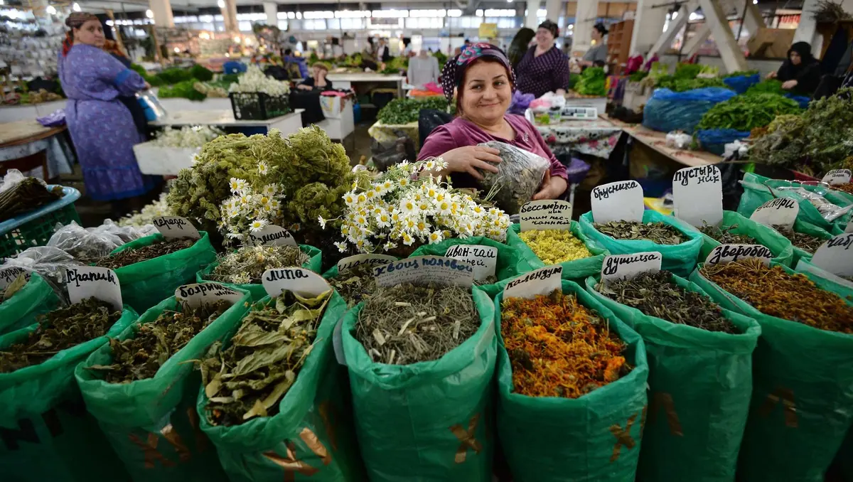 Продавщица за прилавком с мешками сушёных трав и чаёв на рынке в Махачкале