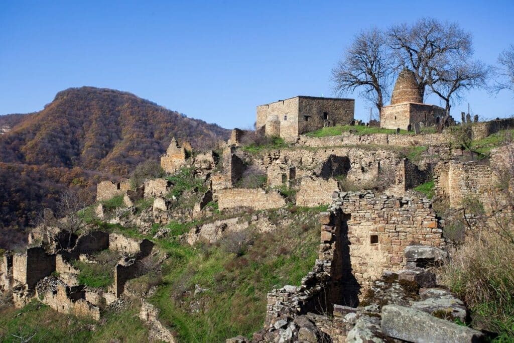 Панорама заброшенного селения Кала-Корейш на скальном хребте: руины домов, мечеть и мавзолей с конусообразным куполом на вершине